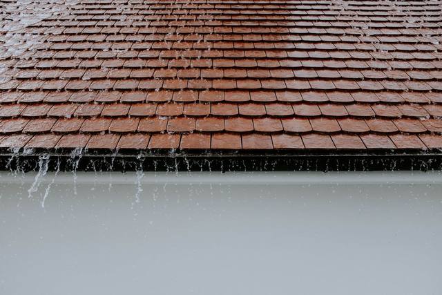 Rain sheeting off the edge of a tile roof